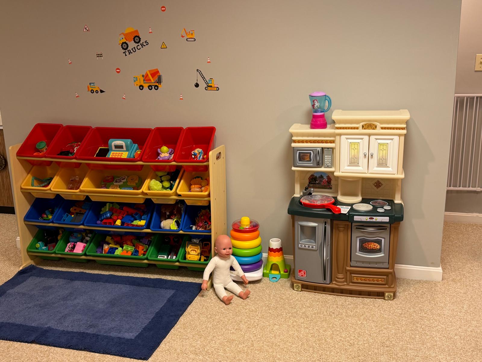 A wider view of the room with the padded column, alphabet wall letters, activity table, and play mats
